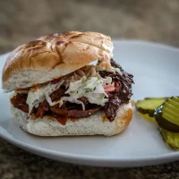 Smoked brisket sandwich with shredded cabbage slaw on a toasted bun.
