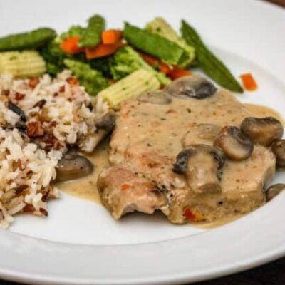 slow cooker pork chops on a plate with rice and vegetables