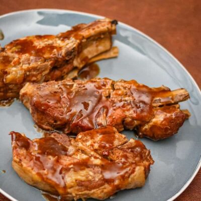 Slow-cooked pork ribs with barbecue sauce on a blue plate.