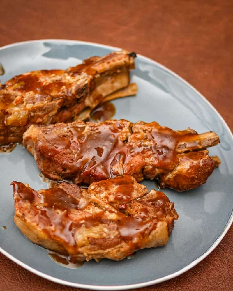 Slow-cooked pork ribs with barbecue sauce on a blue plate.