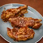 Succulent cooked pork chops with glossy barbecue sauce on a blue plate.