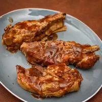 Succulent cooked pork chops with glossy barbecue sauce on a blue plate.