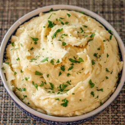 smoked cheddar mashed potatoes garnished with parsley in a serving bowl