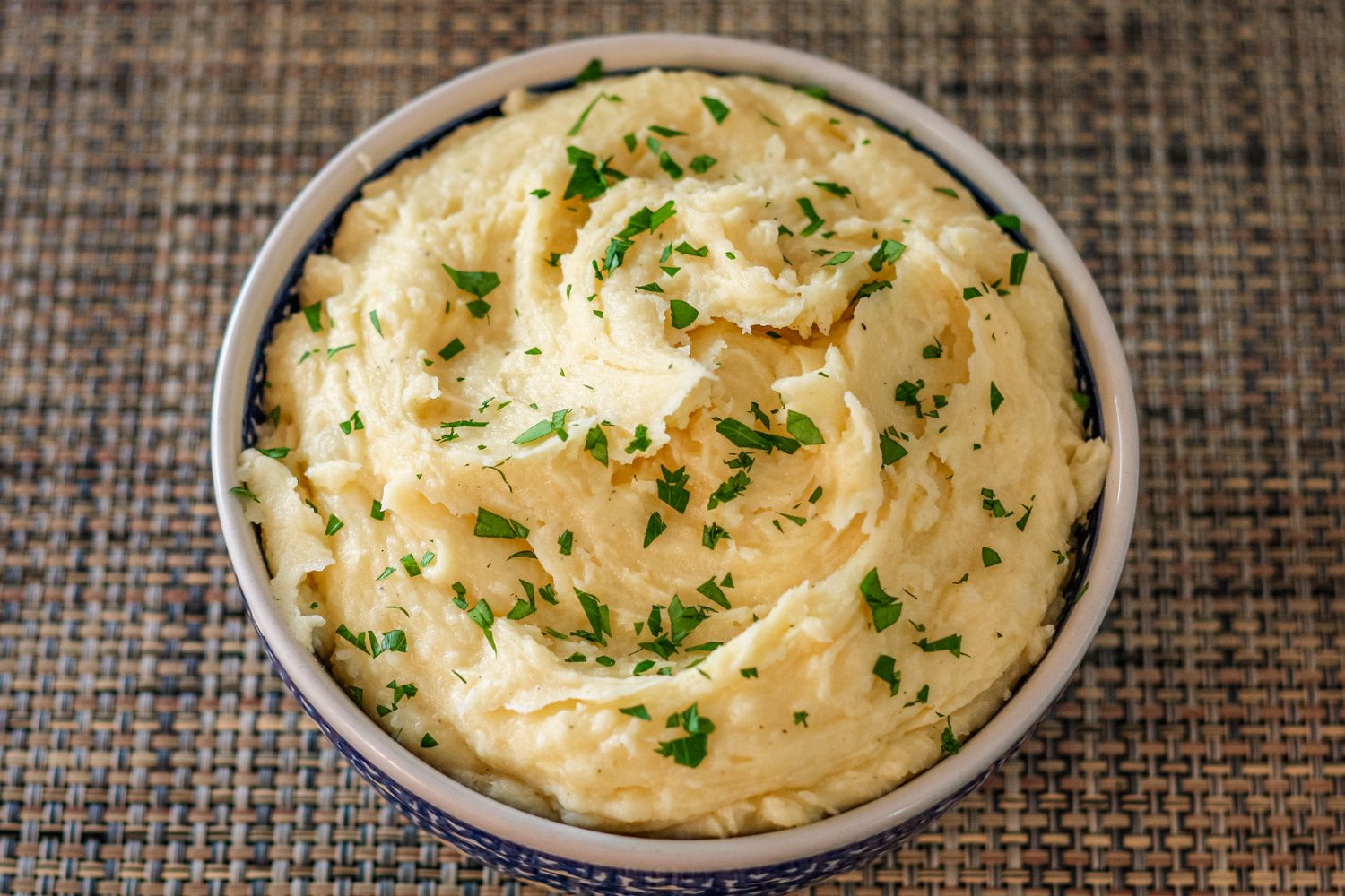 smoked cheddar mashed potatoes garnished with parsley in a serving bowl