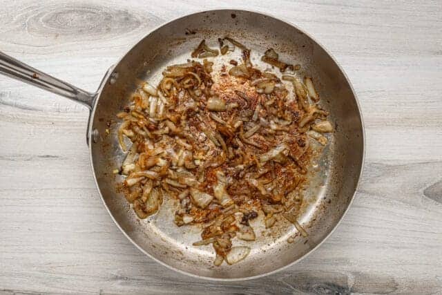 Sautéed onions and garlic in a silver frying pan.