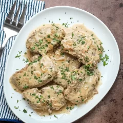 Creamy chicken with herbs and mushroom gravy served on a white plate.