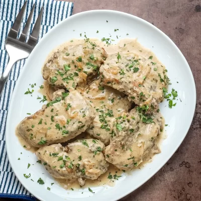 Creamy chicken with herbs and mushroom gravy served on a white plate.
