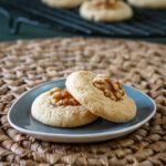 soft sour cream cookies on a plate with a walnut half