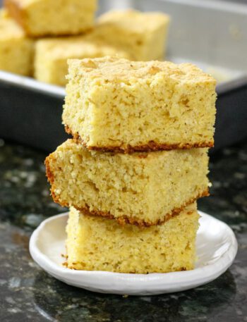 sour cream cornbread squares stacked with the pan in the background