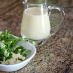 a small pitcher of sour cream dressing with a salad on the side