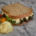 tuna salad in a sandwich with chips on the side