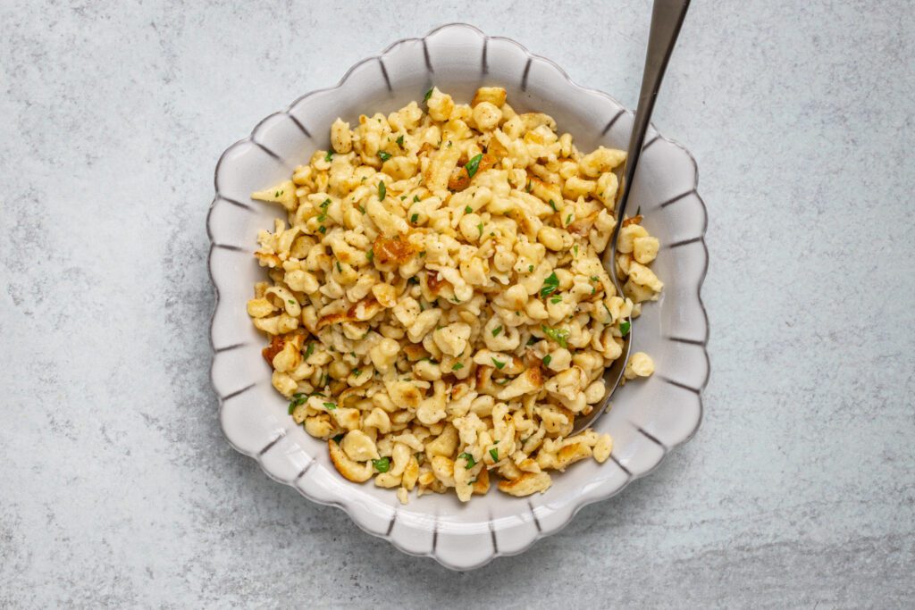 A serving bowl with sautéed spaetzle with herbs.
