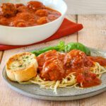A plate of spaghetti and meatballs with garlic bread