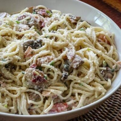 spaghetti with bacon and mushrooms in a serving bowl
