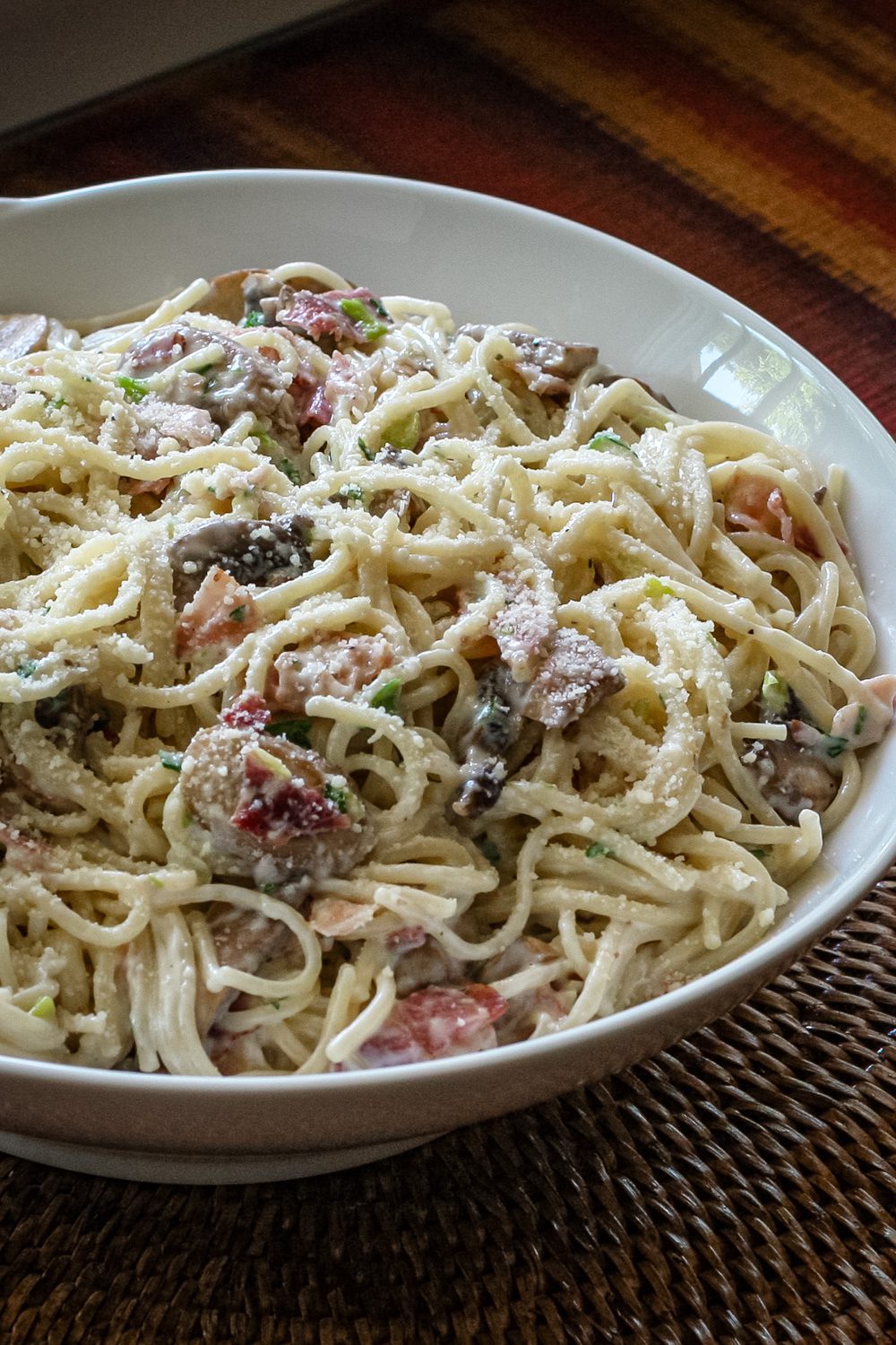 spaghetti with bacon and mushrooms in a serving bowl