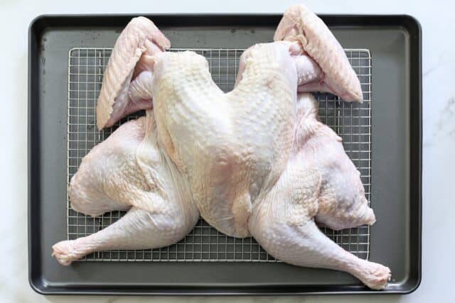 spatchcocked turkey on a rack in the baking pan