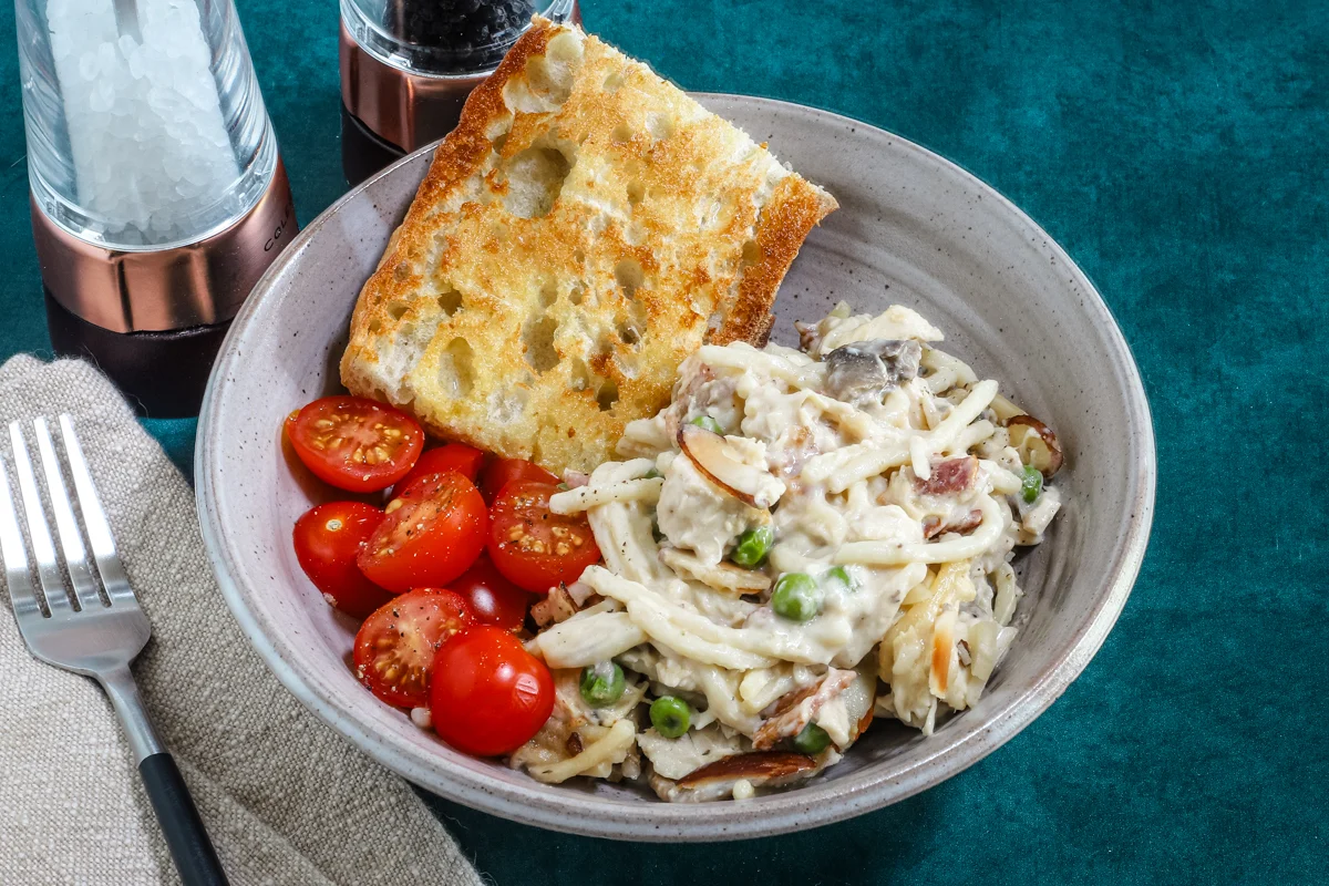 A serving of speedy chicken tetrazzini with some toasted bread and sliced tomatoes on the side.