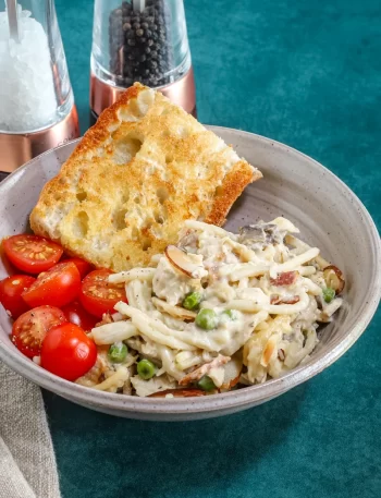 A serving of speedy chicken tetrazzini with some toasted bread and sliced tomatoes on the side.