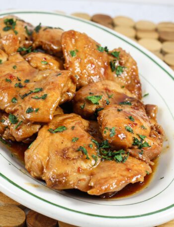 chicken thighs on a platter with sweet-spicy sauce and cilantro garnish
