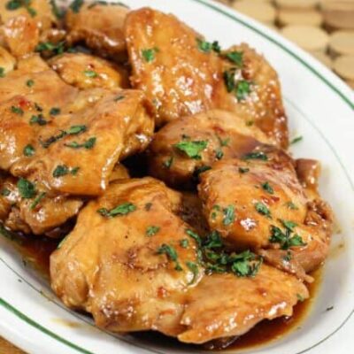chicken thighs on a platter with sweet-spicy sauce and cilantro garnish