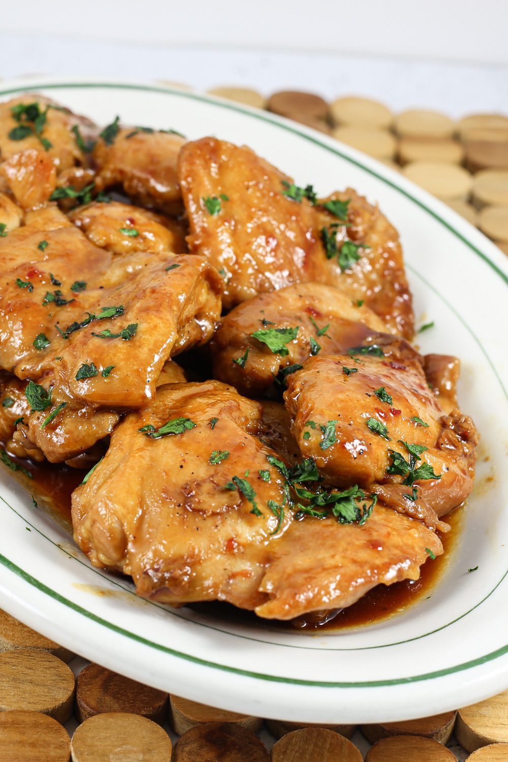 chicken thighs on a platter with sweet-spicy sauce and cilantro garnish
