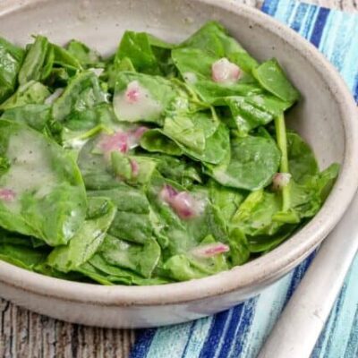 A serving of wilted spinach salad in a bowl