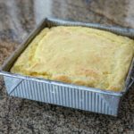 spoon bread in a baking pan cooling.