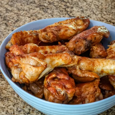 Fried chicken drumsticks in a blue bowl on a speckled countertop.