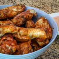A serving bowl with spicy sriracha chicken wings, ready to enjoy with a dip.
