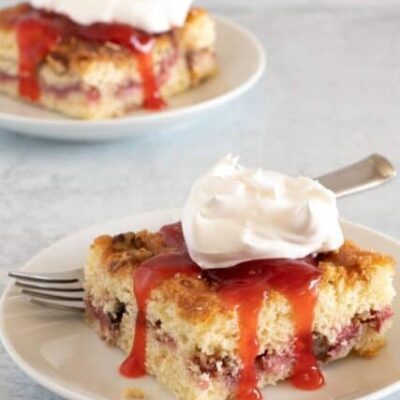 strawberry crumb cakes on plates with strawberry sauce and whipped cream