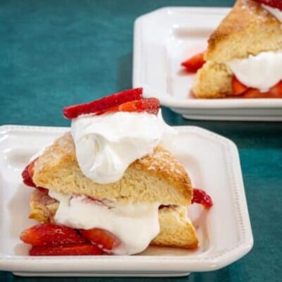 strawberry shortcakes on a plate: cream biscuits with strawberries and whipped cream