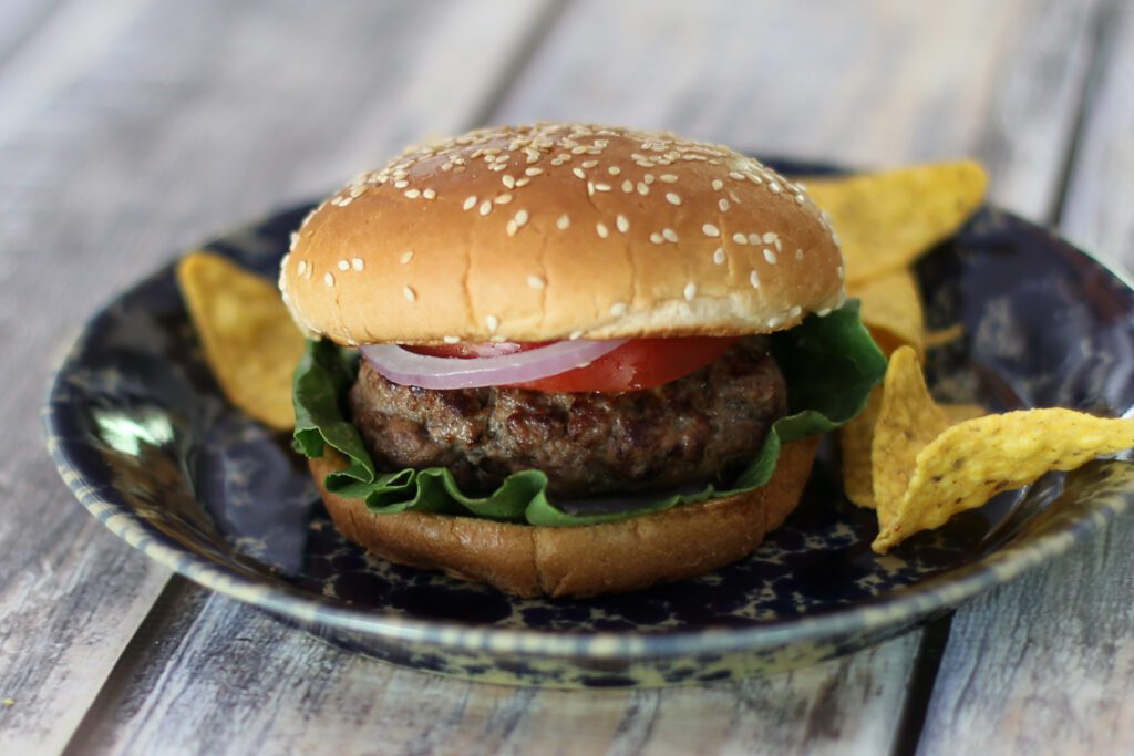 stuffed bacon and cheese burgers on a plate with chips