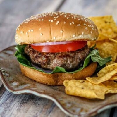 bacon and cheese stuffed burgers on a plate with chips on the side