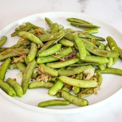 a plate of roasted sugar snap peas with shallots and garlic