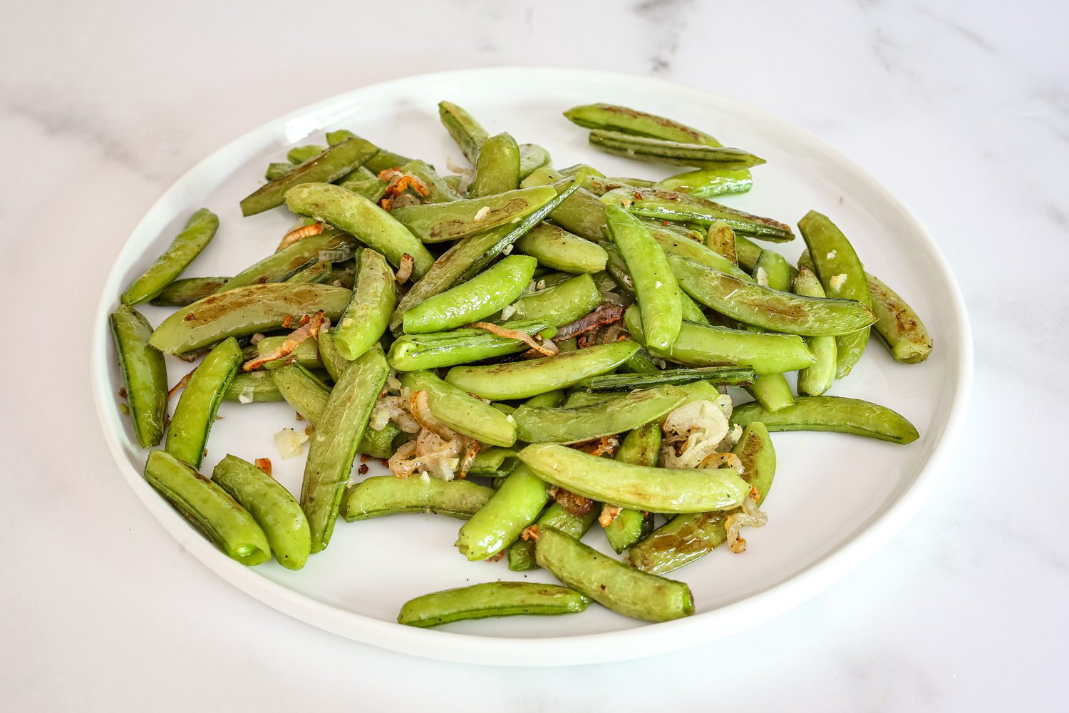 a plate of roasted sugar snap peas with shallots and garlic
