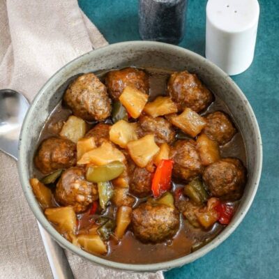 Slow cooker sweet and sour meatballs with bell pepper and pineapple chunks.
