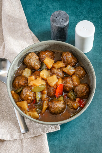 Slow cooker sweet and sour meatballs with bell pepper and pineapple chunks.