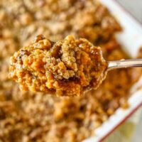 Sweet potato casserole in a baking dish with a closeup of the filling on a spoon.