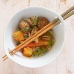 sweet and sour meatballs shown in a bowl with chopsticks on coconut rice