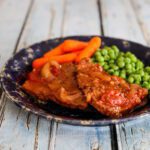 swiss steak with tomatoes on a plate with vegetables