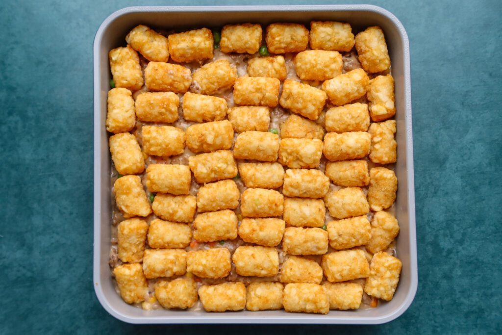 arrange the tater tots on the filling in the baking dish