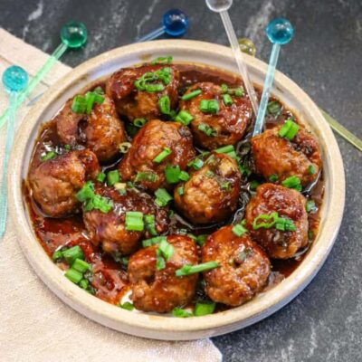 Teriyaki meatballs served as an appetizer with picks and a garnish of green onion tops.