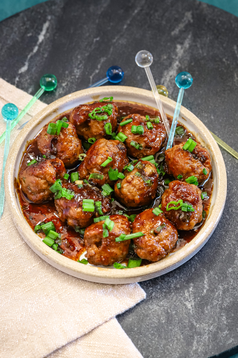 Teriyaki meatballs served as an appetizer with picks and a garnish of green onion tops.