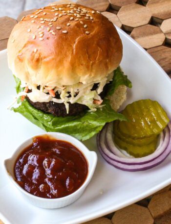 texas burger on a plate with coleslaw topping and bbq sauce
