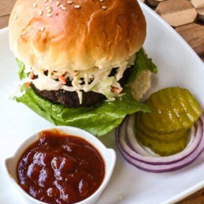 texas burger on a plate with coleslaw topping and bbq sauce