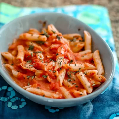 Pasta with tomato sauce and fresh herbs in a gray bowl.