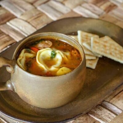 tortellini soup in a cup with crackers