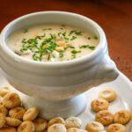 a bowl of tuna chowder with corn and chives for garnish