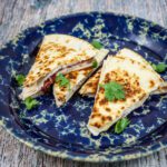 turkey and brie quesadilla with cranberry sauce on a plate with cilantro