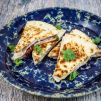 turkey and brie quesadilla with cranberry sauce on a plate with cilantro